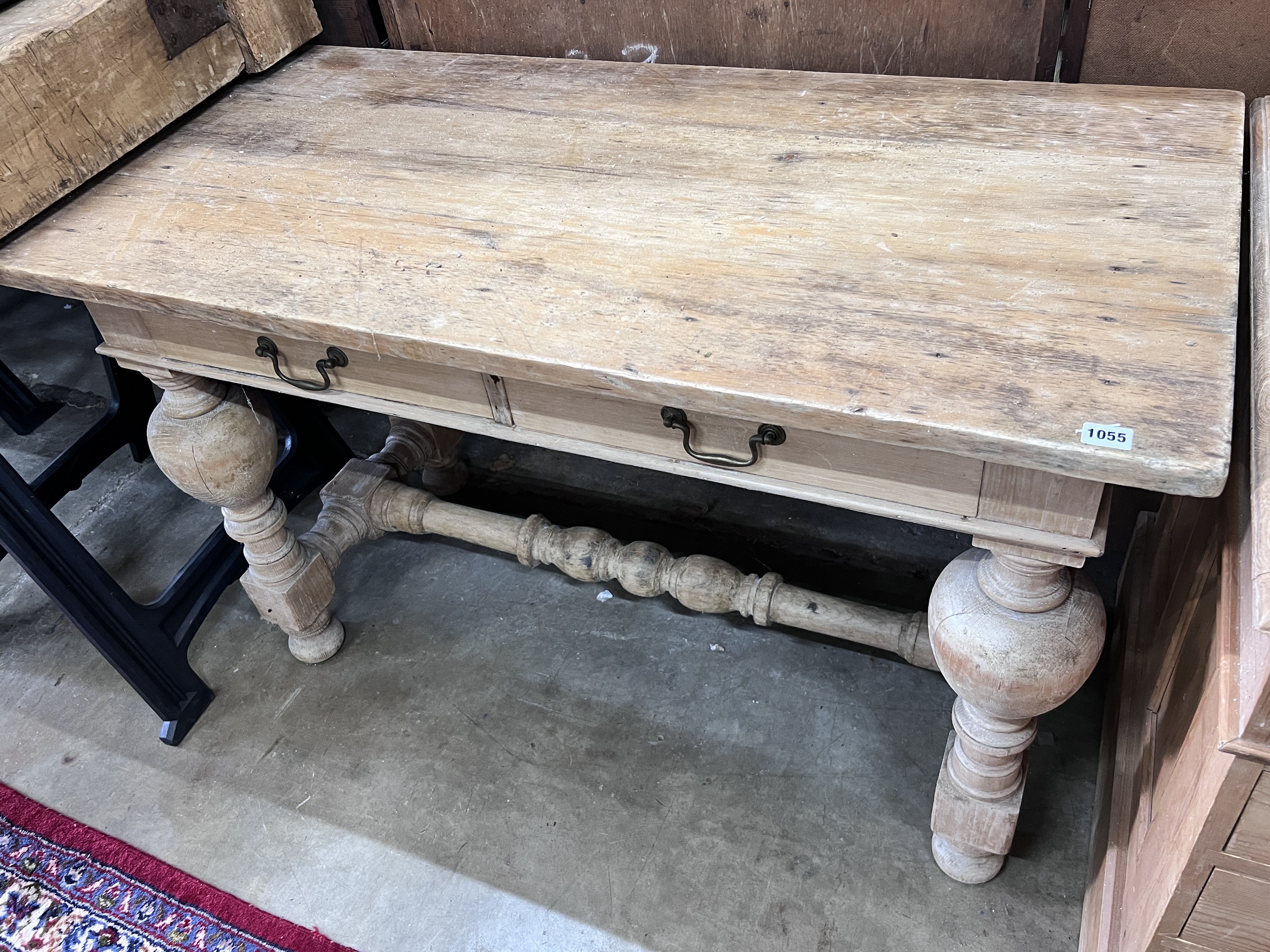 A Flemish style pine two drawer table, on bulbous end supports, width 122cm, depth 61cm, height 76cm